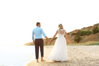 Wedding couple holding hands together on beach