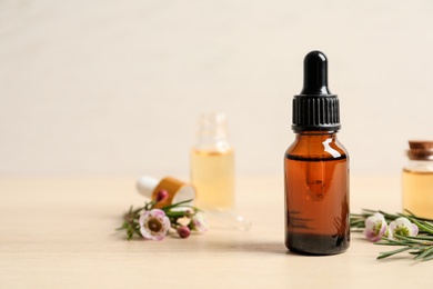 Photo of Composition with bottle of natural tea tree oil on wooden table. Space for text
