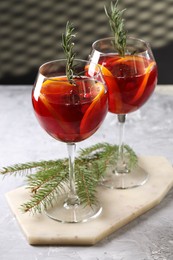 Christmas Sangria cocktail in glasses and fir tree branch on grey textured table