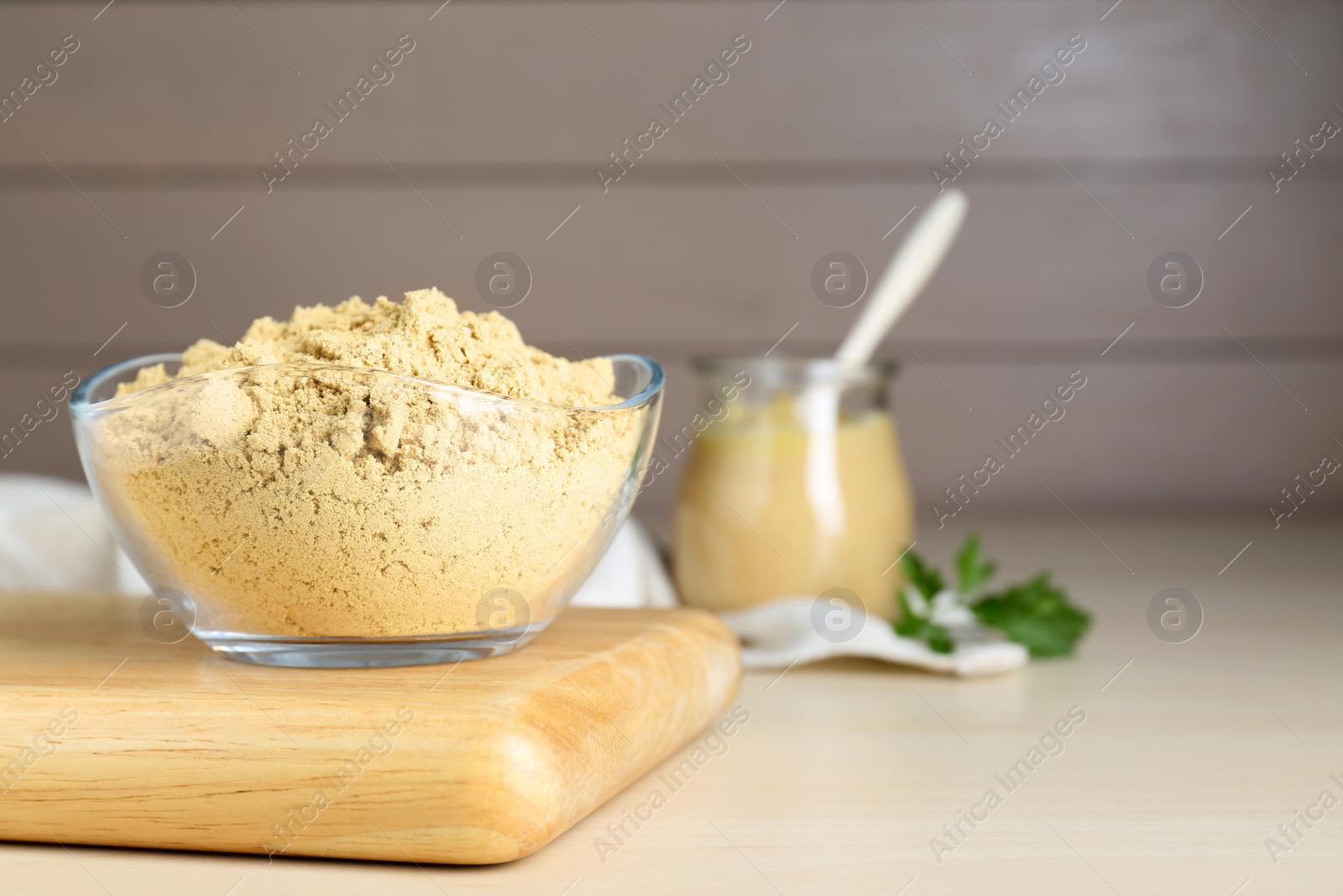 Photo of Bowl of aromatic mustard powder on wooden table. Space for text