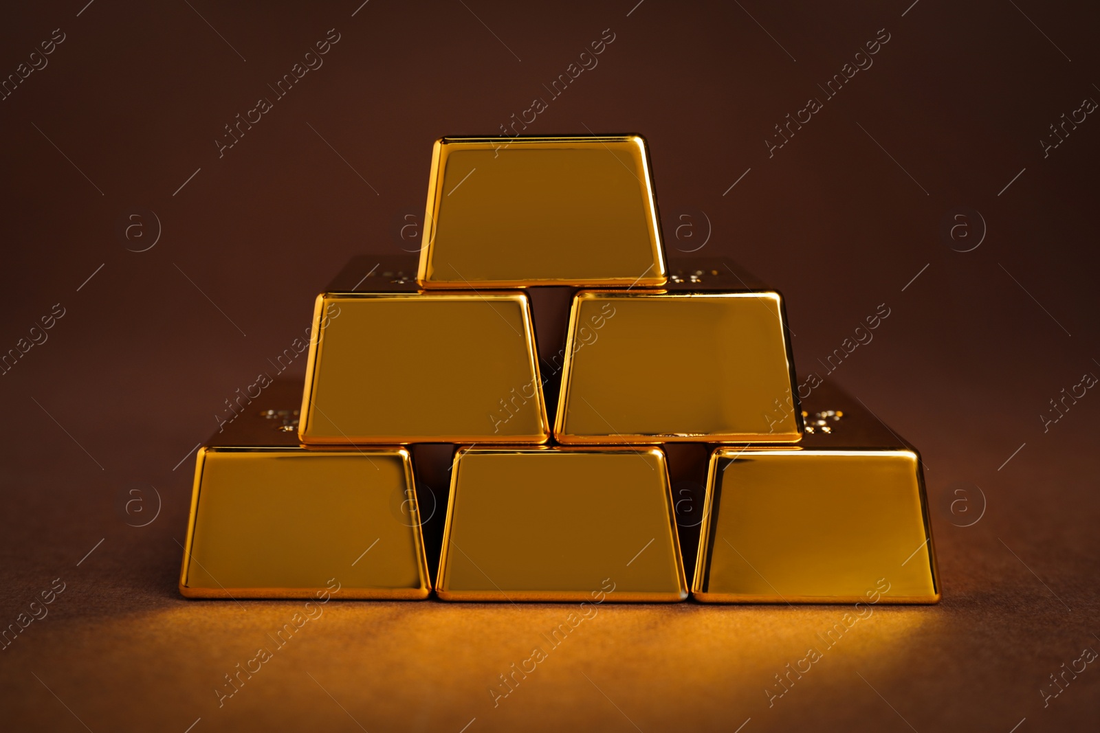 Photo of Stack of shiny gold bars on brown background