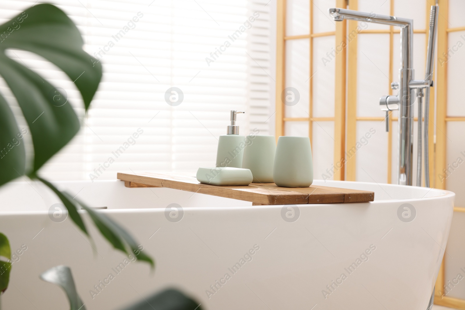 Photo of Set of bath accessories on tub in bathroom