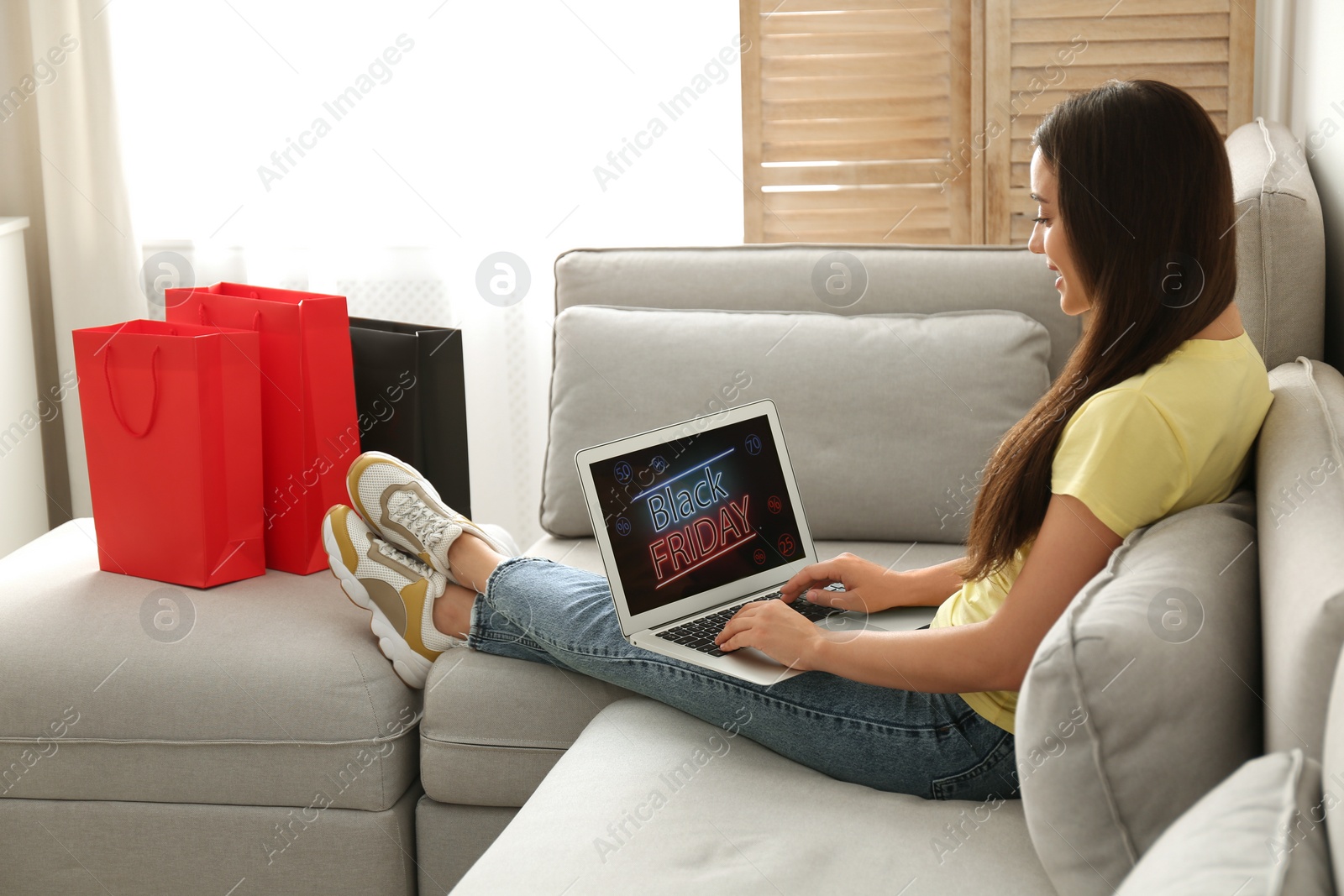 Photo of Woman using laptop with Black Friday announcement on screen at home