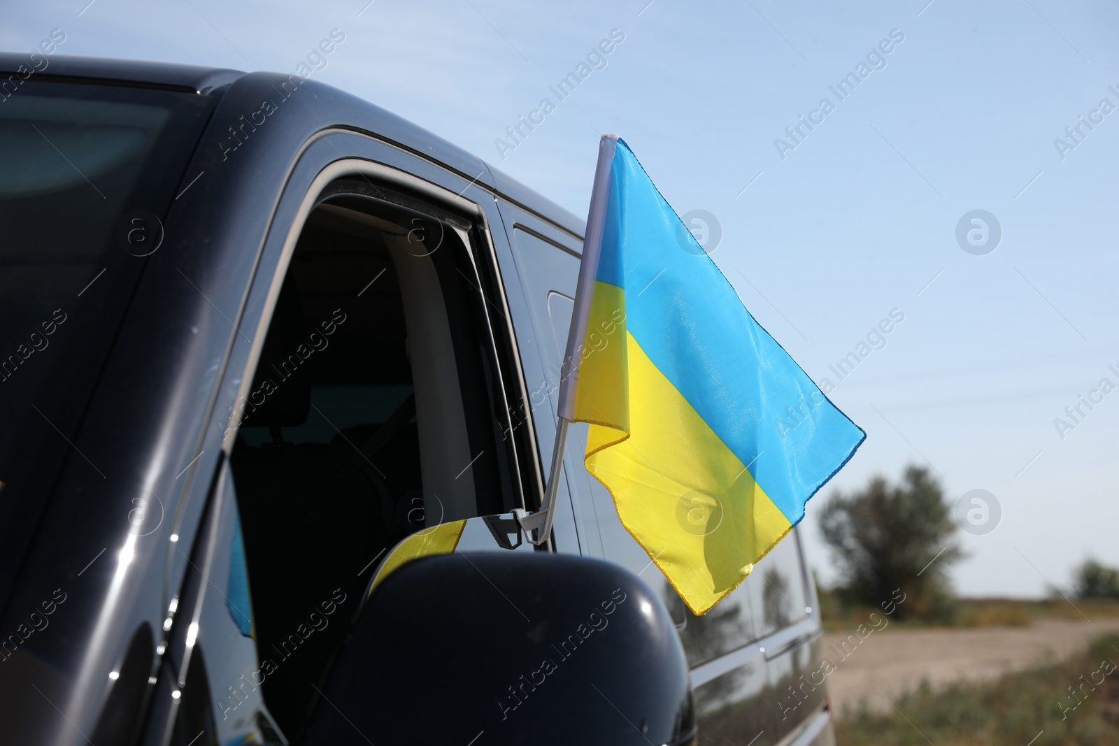 Photo of National flag of Ukraine on car window outdoors, closeup