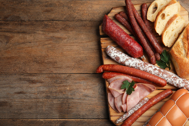 Photo of Different tasty sausages on wooden table, top view. Space for text