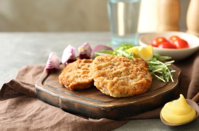 Photo of Tasty schnitzels served with sauce on grey table, closeup
