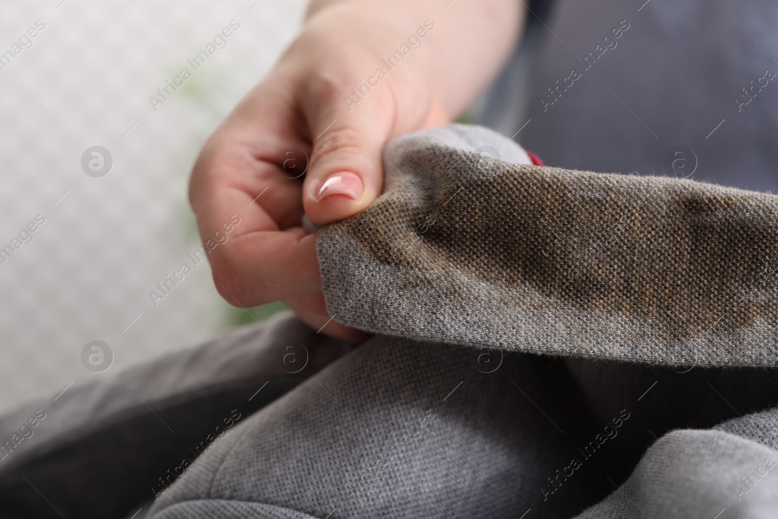 Photo of Woman showing stain from coffee on jacket against blurred background, closeup