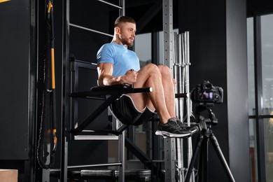 Photo of Man recording workout on camera at gym. Online fitness trainer