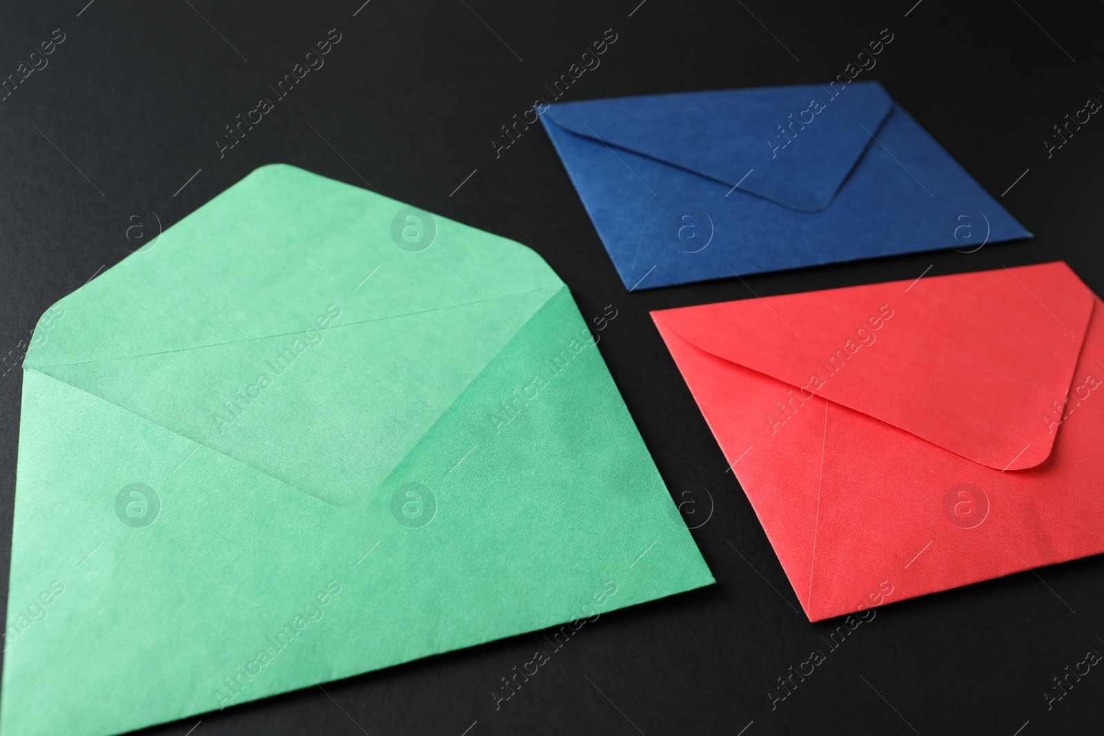 Photo of Colorful paper envelopes on black background. Mail service