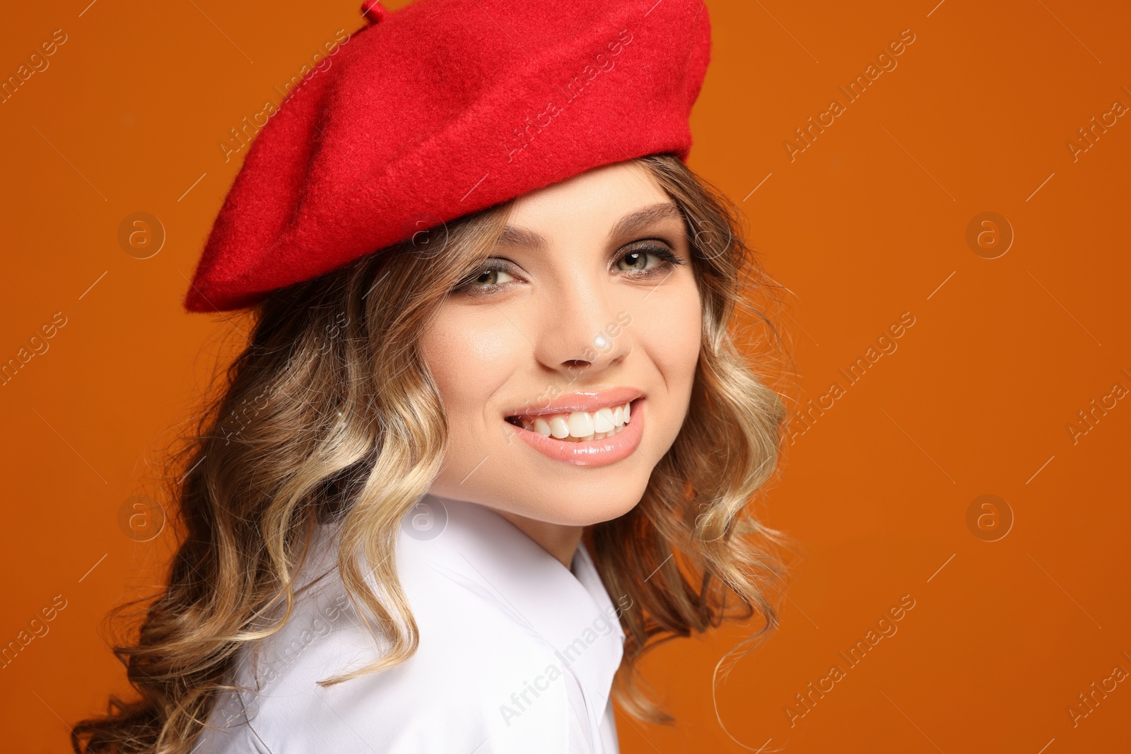 Photo of Portrait of beautiful young woman in stylish beret against orange background, closeup