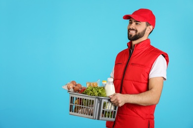 Man holding basket with fresh products on color background, space for text. Food delivery service