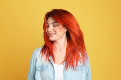Young woman with bright dyed hair on yellow background