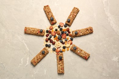 Photo of Sun made with tasty granola bars on beige marble table, flat lay