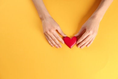 Photo of Woman holding decorative heart on color background, top view. Space for text