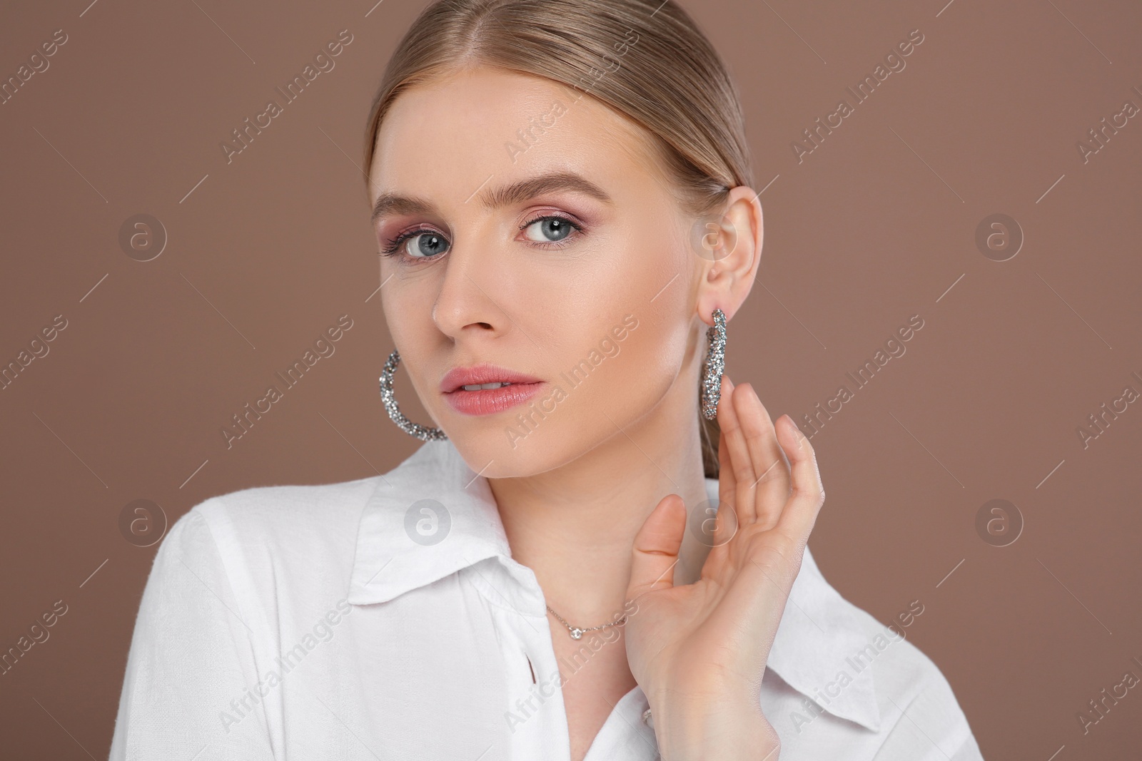 Photo of Beautiful young woman with elegant jewelry on light brown background