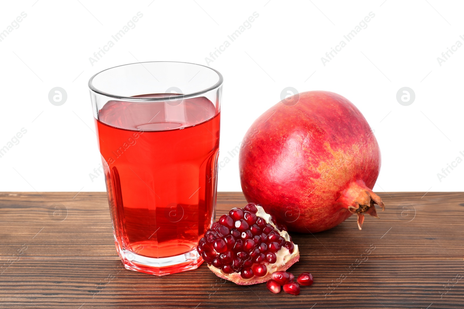 Photo of Refreshing pomegranate juice in glass, leaves and seeds on wooden table against white background