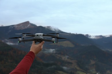 Photo of Man with modern drone in mountains, closeup. Space for text