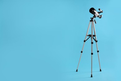Photo of Tripod with modern telescope on light blue background, space for text