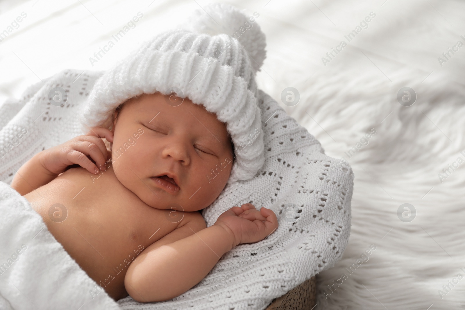 Photo of Cute newborn baby in warm hat sleeping on knitted blanket