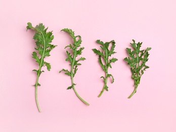 Fresh arugula on light pink background, flat lay