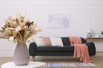 Photo of Beautiful sofa with cushions and bouquet in living room, focus on flowers. Interior design