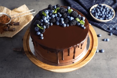 Photo of Fresh delicious homemade chocolate cake with berries on gray table