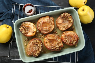 Tasty baked quinces with nuts and honey in dish on table, flat lay