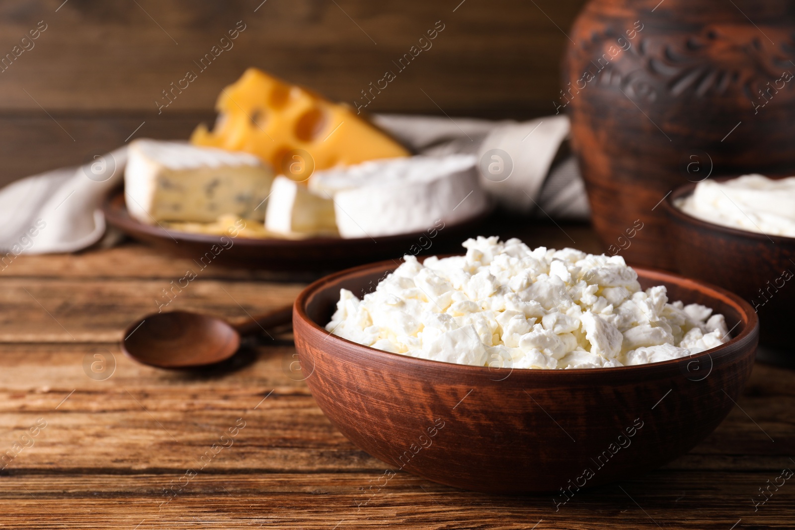 Photo of Clay bowl with cottage cheese on wooden table, space for text