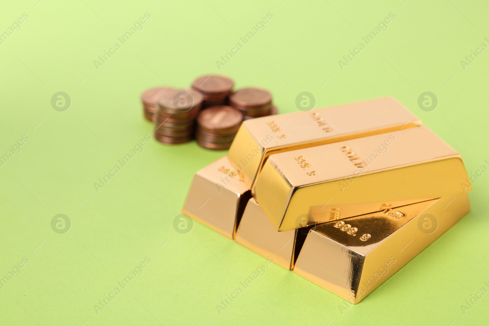 Photo of Stacked gold bars and coins on color background. Space for text