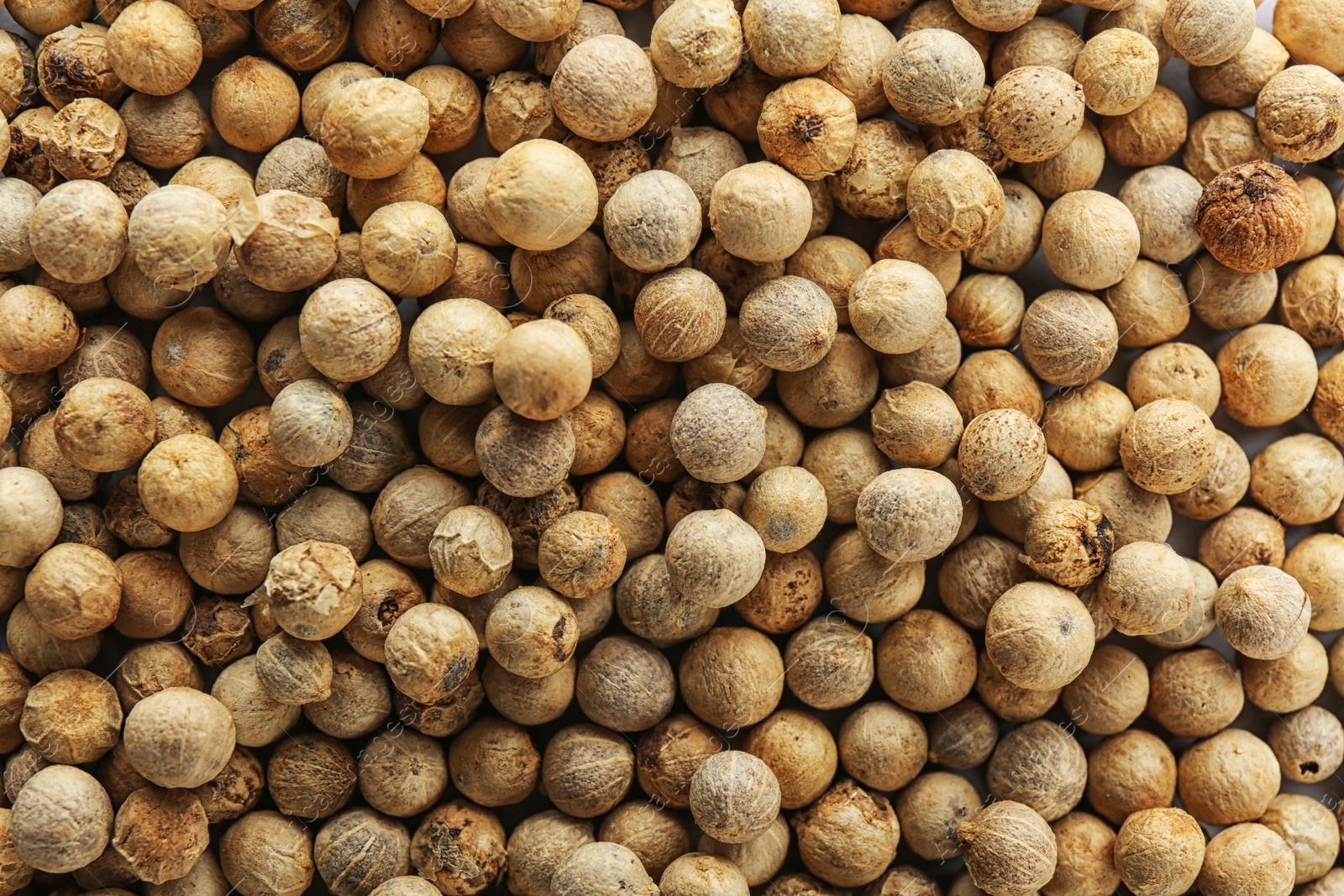 Photo of White peppercorns as background, top view. Aromatic spice