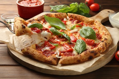 Taking piece of delicious Margherita pizza at wooden table, closeup