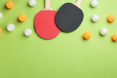 Ping pong rackets and balls on green background, flat lay. Space for text