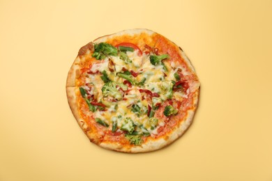 Photo of Delicious vegetarian pizza on yellow table, top view