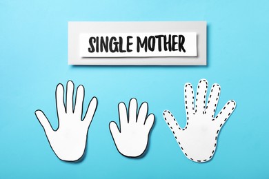 Being single mother concept. Palms made of paper on light blue background, flat lay