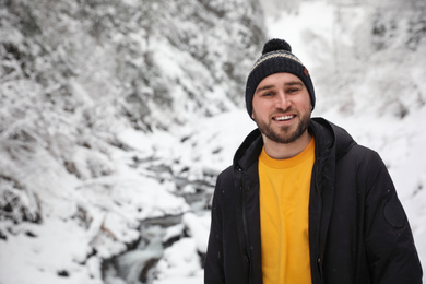 Photo of Handsome man wearing warm clothes outdoors on snowy day. Winter vacation