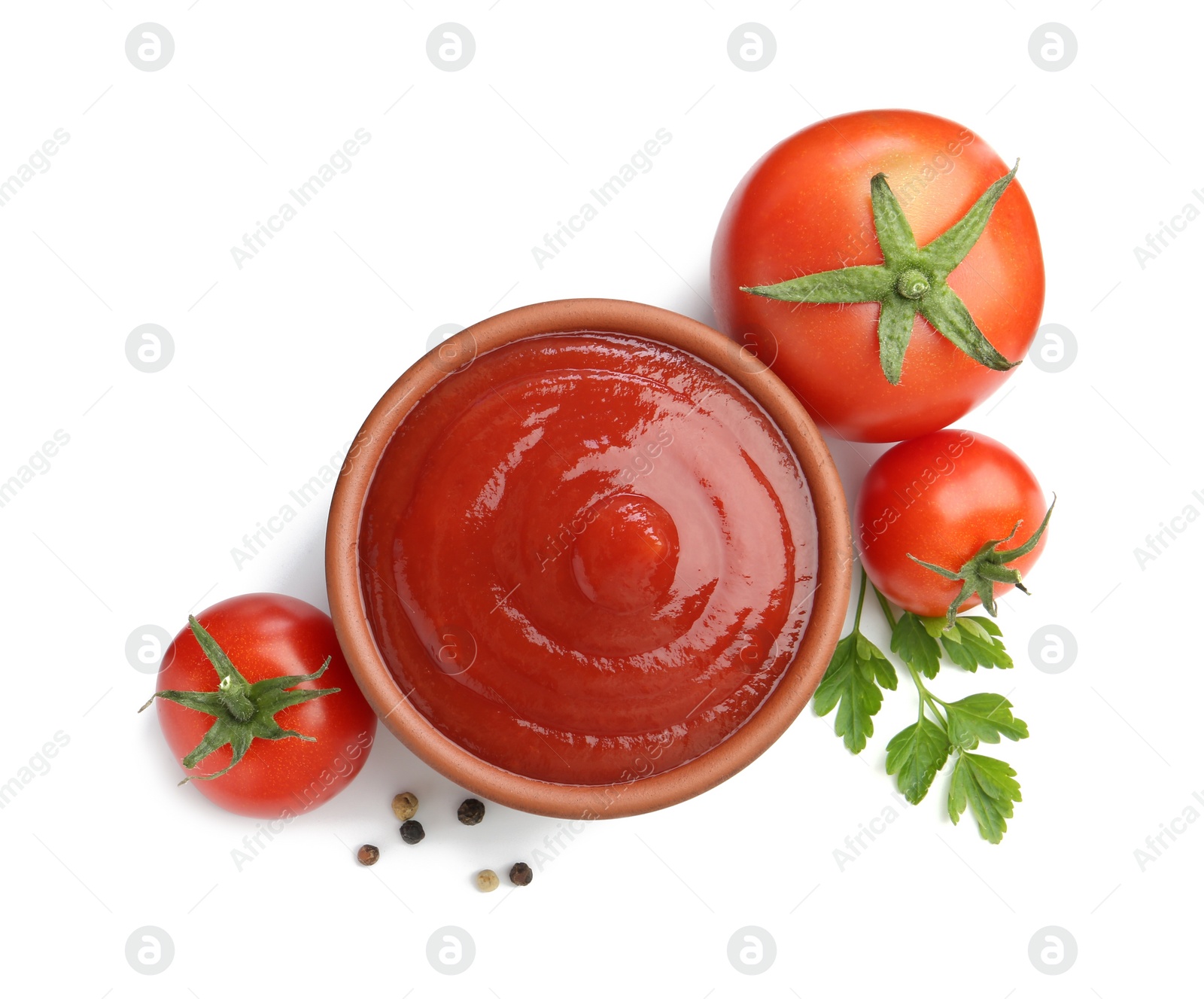 Photo of Tasty ketchup in bowl, parsley, peppercorns and fresh tomatoes isolated on white, top view