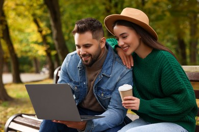 Photo of Happy young couple with laptop spending time together in autumn park