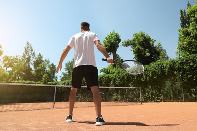 Man playing tennis on court, back view