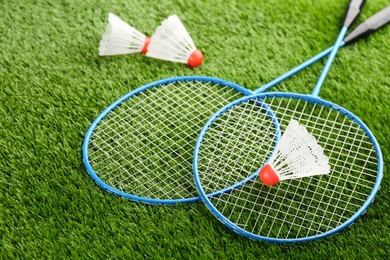 Photo of Badminton rackets and shuttlecocks on green grass outdoors