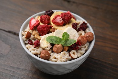 Photo of Oatmeal with freeze dried fruits, nuts and mint on wooden table