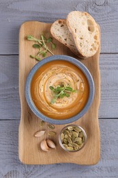 Photo of Tasty pumpkin soup served on grey wooden table, top view