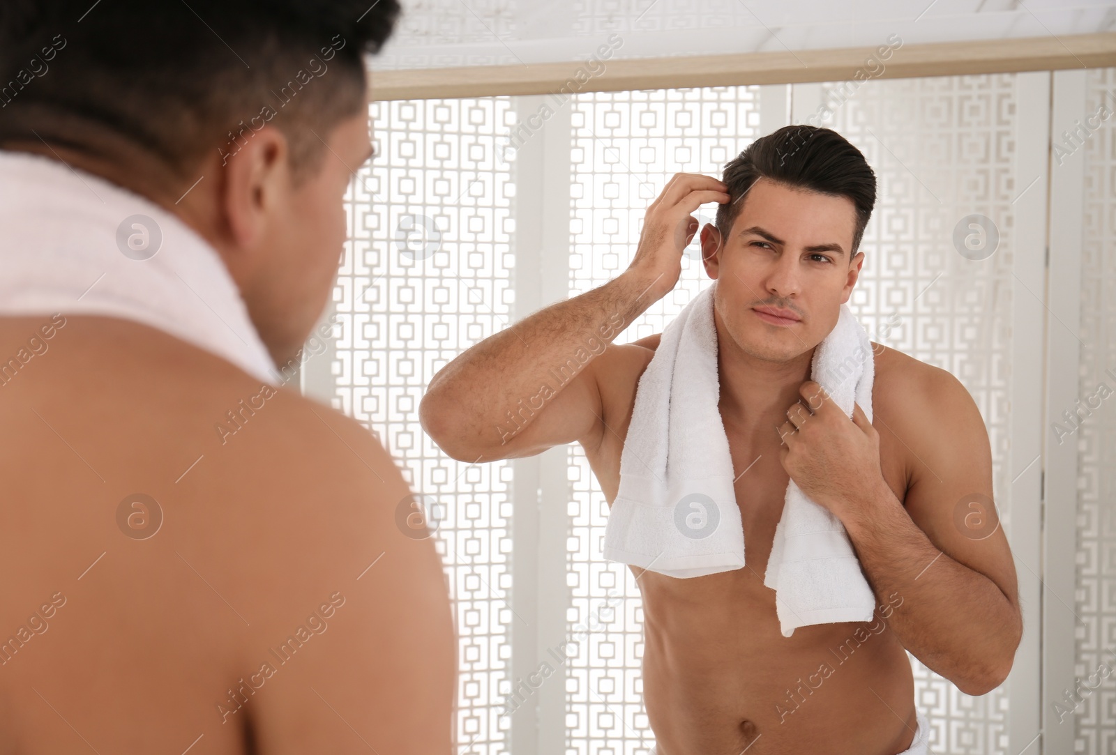 Photo of Handsome man with towel near mirror in bathroom