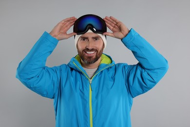 Winter sports. Happy man in ski suit and goggles on gray background