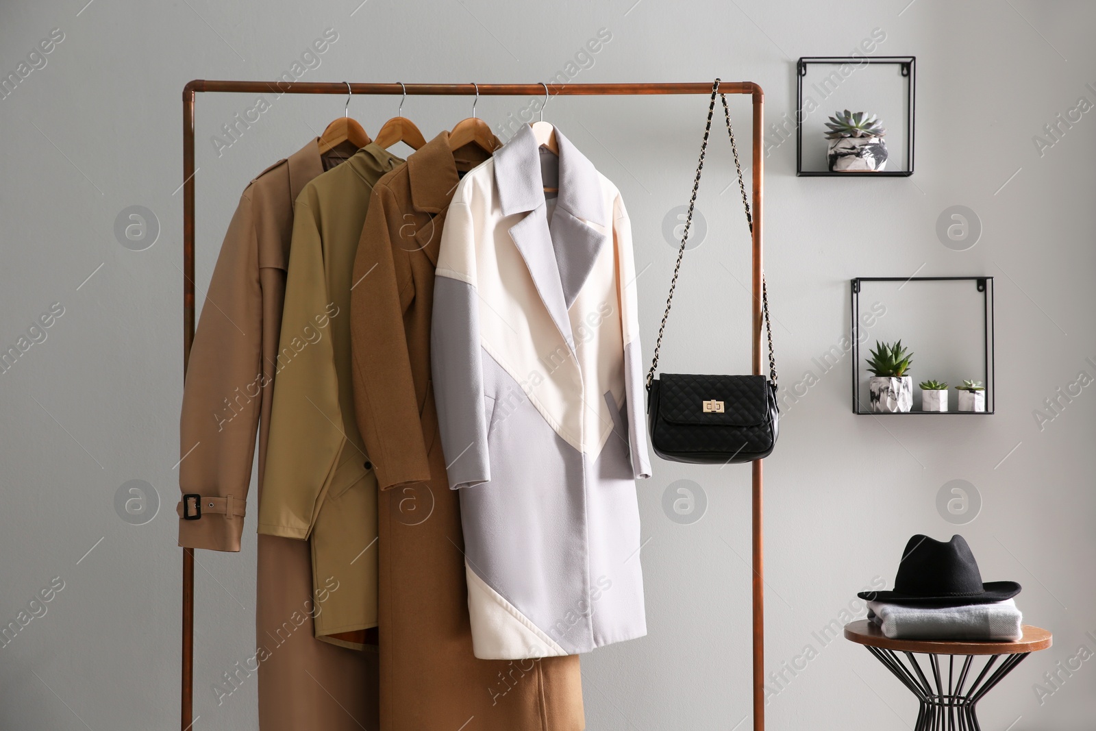 Photo of Different warm coats on rack in stylish room interior