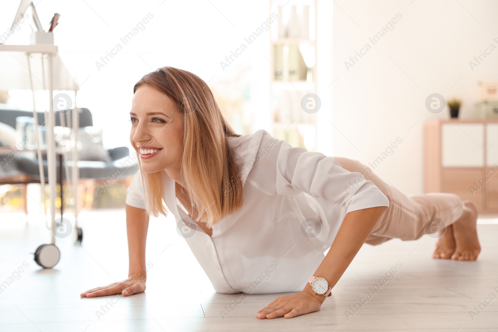 Photo of Beautiful young businesswoman doing exercises in office. Workplace fitness