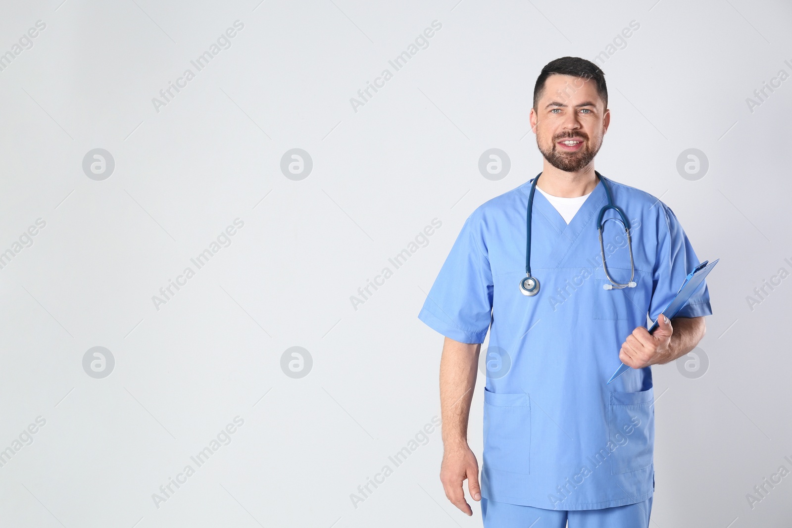 Photo of Portrait of mature doctor with clipboard against light background