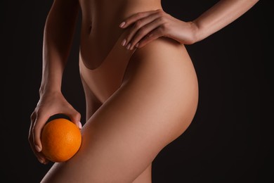 Photo of Closeup view of slim woman in underwear with orange on black background. Cellulite problem concept