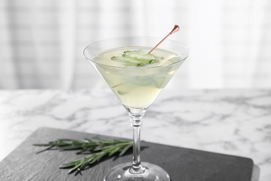 Glass of tasty cucumber martini on white marble table