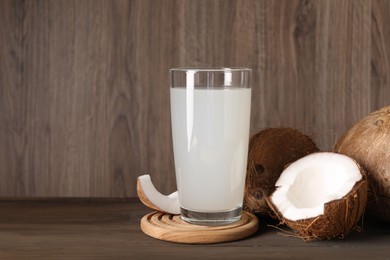 Photo of Glass of coconut water and nuts on wooden table, space for text