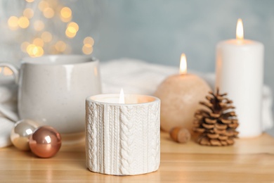 Photo of Composition with candle in ornate holder on wooden table. Christmas decoration